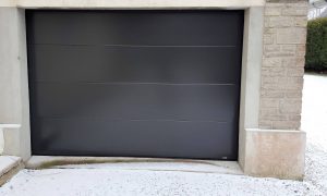 Porte de garage sectionnelle motorisée installée par votre artisan Solabaie Renov' Habitat dans la Manche sur la commune de Terres-et-Marais