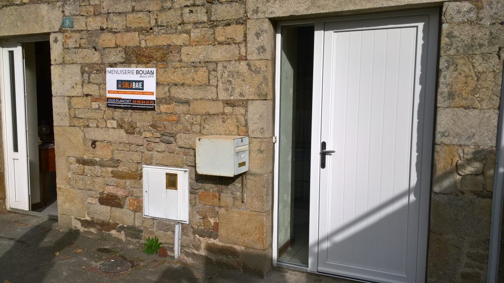 Porte d'entrée PVC Armoise et fenêtre PVC posées sur une maison en pierres par la Mneuiserie Bouan