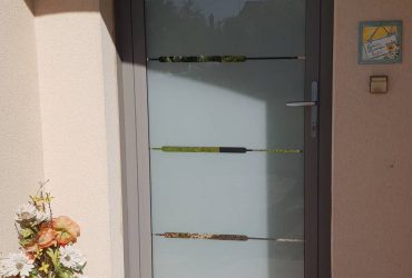 Porte d'entrée aluminium grise Grand vitrage modèle Baguio à vitrage feuilleté, installée par votre professionnel Solabaie ADECI.